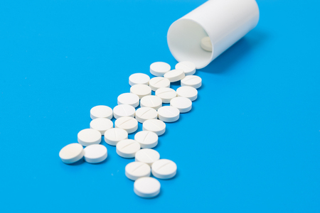 White circle tablets and plastic bottle for tablets on blue backgroundの写真素材