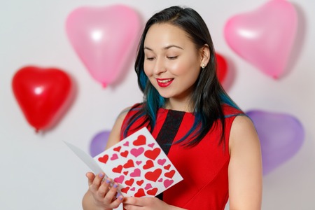a beautiful young woman takes a card with hearts with a Declaration of love. Valentine's day 14 Februaryの写真素材