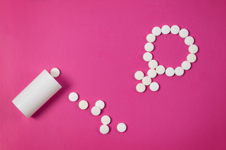 Concept Female health, female contraception. Gender symbol made from pink pills or tablets on pink backgroundの写真素材