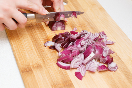 cutting onions on a cutting Board with a knife.の写真素材