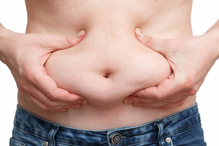 male hand presses the excess fat on your stomachの写真素材