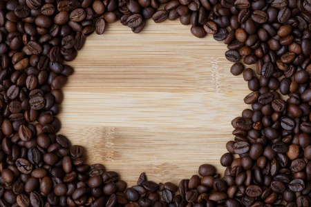 coffee beans on a light wooden table surface with an empty seat in the centerの写真素材