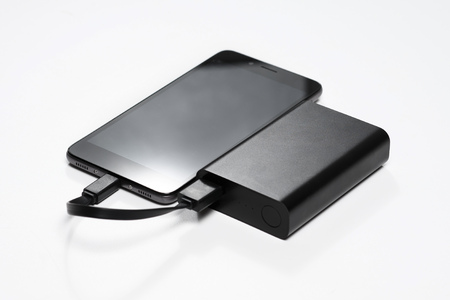 smartphone is charging from the black battery power bank.の写真素材