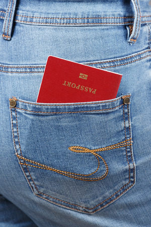 Red biometric passport in jeans pocket close-up.の写真素材