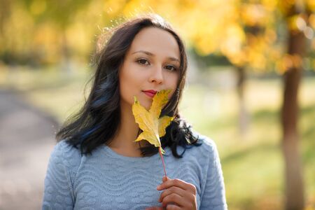 Portrait of smiling young woman with autumn leafs in front of foliage. season. autumn conceptの写真素材
