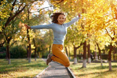 season and people concept - happy girl jumping at autumn parkの写真素材