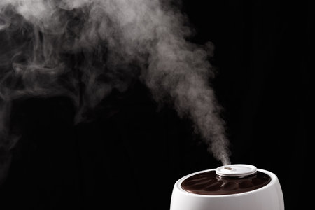 ultrasonic humidifier releases water vapor from the hole. on black background
