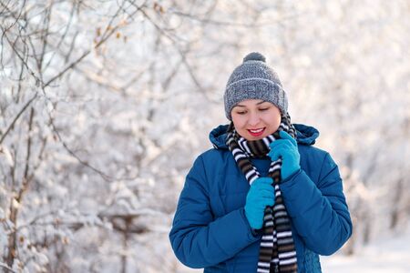 portrait of a young happy girl woman in winter clothes. in the winter snow forest Parkの写真素材