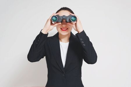 Conceptual shot of a mature businesswoman with big binoculars. on white backgroundの写真素材