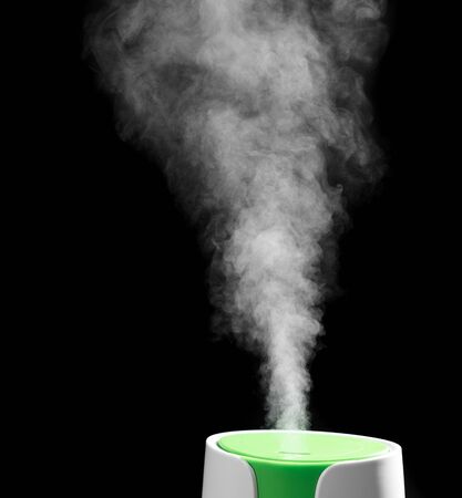 the process of operation of the ultrasonic humidifier close-up. a jet of steam is clearly visible on a black background.の写真素材