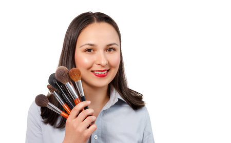 portrait of a young female makeup artist with a set of makeup brushes looks at the camera and...