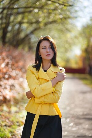 portrait of a slender young brunette in a yellow jacket in a Park.の写真素材
