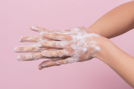 Hygiene to protect human health from viruses, hand washing with soap process. On pink background.