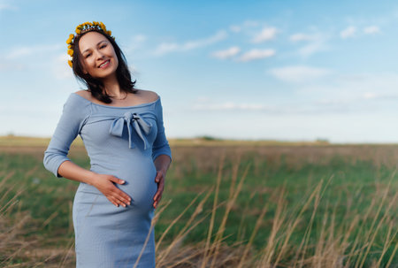 A young pregnant brunette woman walks in the fresh air on a sunny summer day. Concept of pregnancy,...
