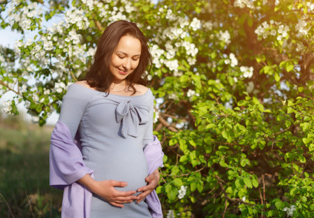 Pregnant woman posing in a green flowering apple garden. concept of pregnancy, maternity,...