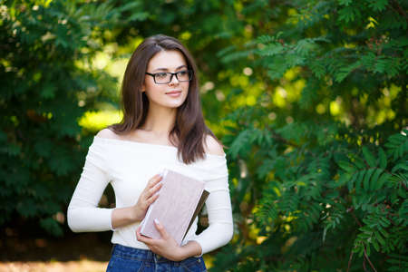 young beautiful woman sitting on a bench in the park and working on a laptopの写真素材