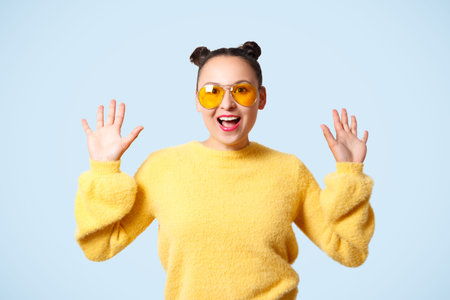 young happy woman in yellow sweater and glasses isolated on blue background