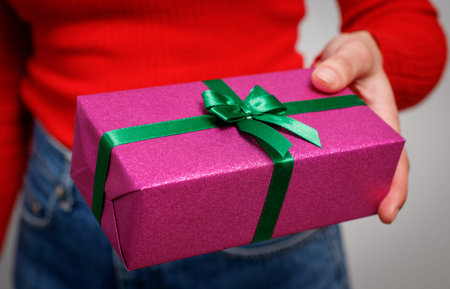 woman presents a gift for Christmas in a bright gift box. close-up.