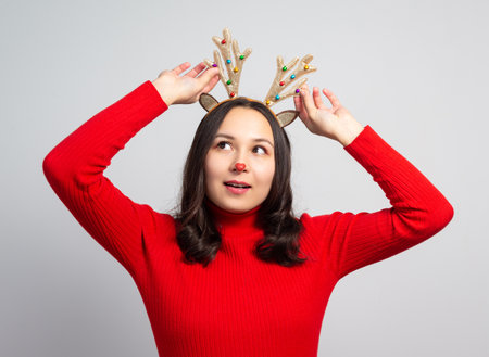 cute young woman trying on christmas deer antlers. on white backgroundの写真素材