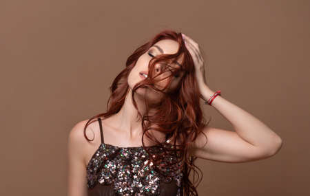 Beauty dynamic portrait of a red-haired happy beautiful woman on a beige background.の写真素材