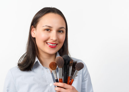 Portrait of a young woman makeup artist with a set of makeup brushes on a white background