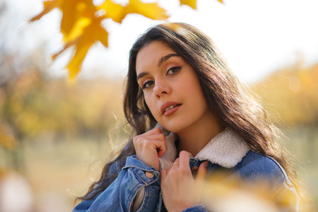 Portrait of beautiful young woman walking outdoors in autumn parkの写真素材