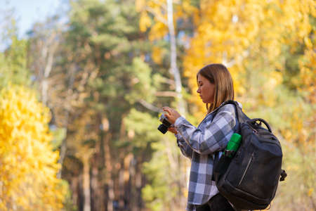 A young female tourist walks in the forest with a camera and a backpack on her shouldersの写真素材