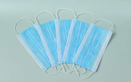 Several medical protective masks lying in a row on a light blue backgroundの写真素材