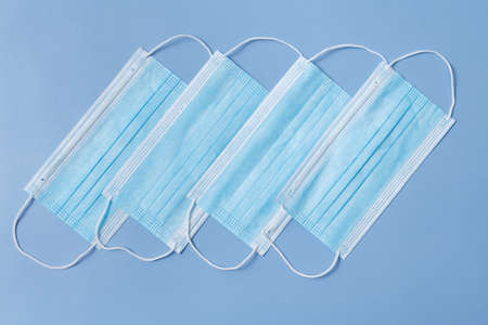 Several medical protective masks lying in a row on a light blue backgroundの写真素材