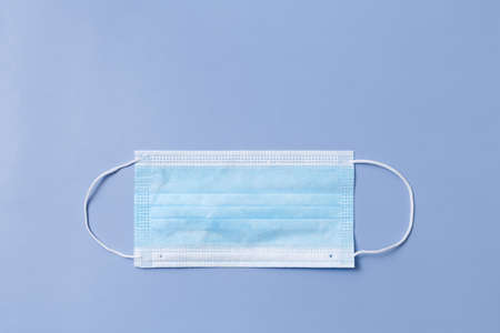 One medical face mask lies horizontally on a blue background.の写真素材