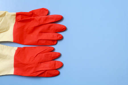 Red household gloves on a blue background to the left. With space for copyspaceの写真素材