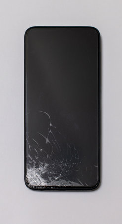 Smartphone with a broken screen display vertically on a gray backgroundの写真素材