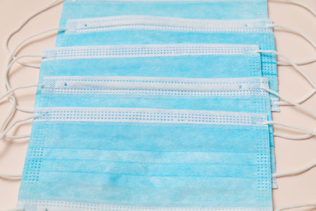 Several face protective medical masks lie on a beige background. With a place to copyspace.の写真素材