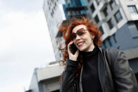 Portrait of an adult female businesswoman in a big city. Talking on a mobile phone and smiling.の写真素材