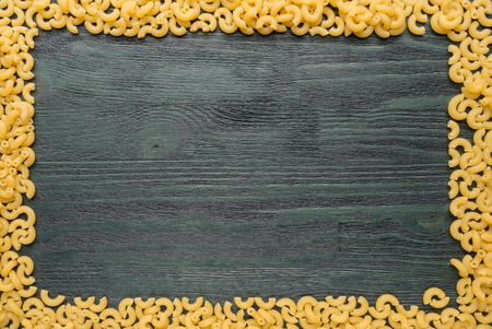 Macaroni frame on a dark wooden tableの写真素材
