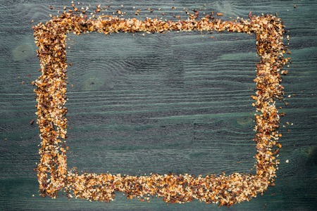 Frame from spice. Chopped chili peppers and dried garlic on a dark wooden tableの写真素材