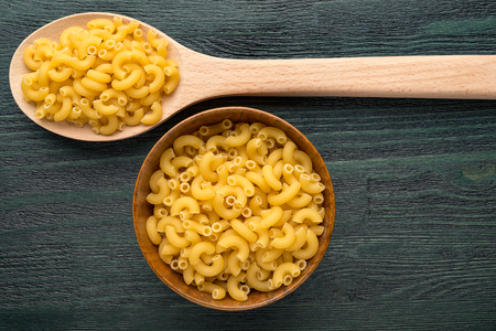 Wooden spoons and bowls with pastaの写真素材
