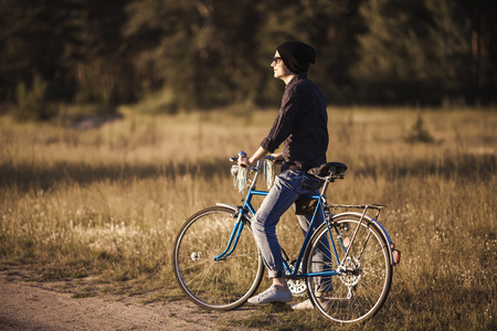 Young handsome stylish man posing with vintage bike in sunny summer dayの写真素材