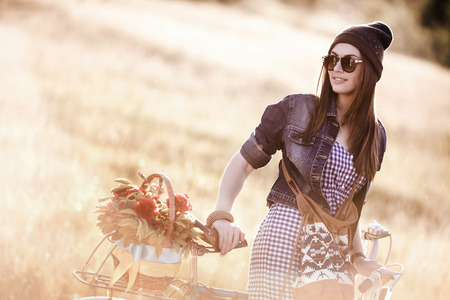 Young pretty brunette woman posing on the nature with bike in summer sunshine  Fashion portrait  の写真素材