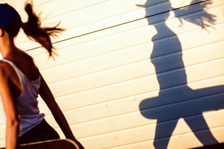 Closeup summer portrait of pretty young woman posing in urban, hipster girl with skate board in town  Summer evening sunlightの写真素材