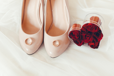 wedding shoes with rings and red rose petalsの写真素材