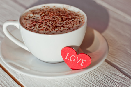 Beautiful coffee Cup with heart on a white wooden backgroundの写真素材