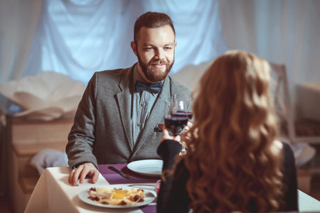 Beautiful young couple with glasses of red wine in luxury restaurant