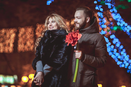 loving young couple walking outdoors in winter. Girl holding a flowerの写真素材
