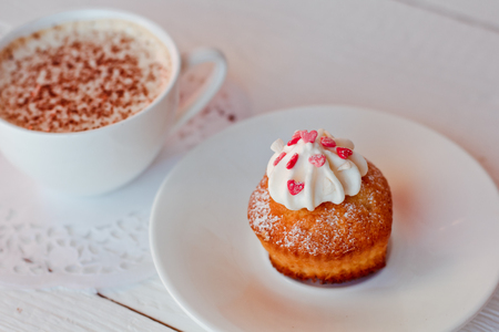 A beautiful Cup of coffee with a muffin on white wooden backgroundの写真素材