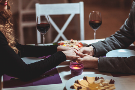 Beautiful young couple with glasses of red wine in luxury restaurantの写真素材