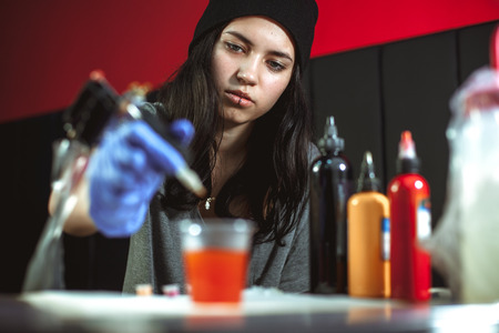 Beautiful brunette girl makes tattoo. Tattooist makes a tattoo. Closeupの写真素材