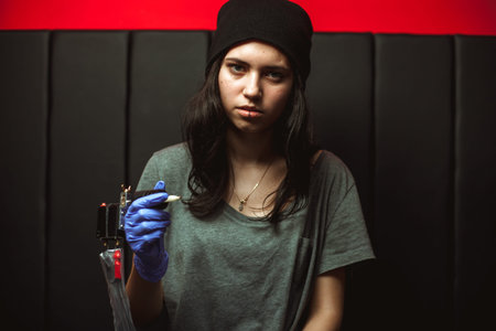 beautiful brunette girl tattoo artist in a black hat with piercingsの写真素材
