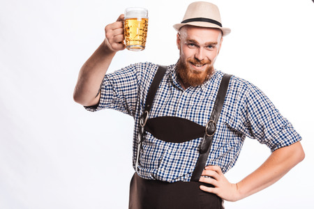 Happy smiling man with leather trousers (lederhose) holds oktoberfest beer glass. Isolated on white backgroundの写真素材