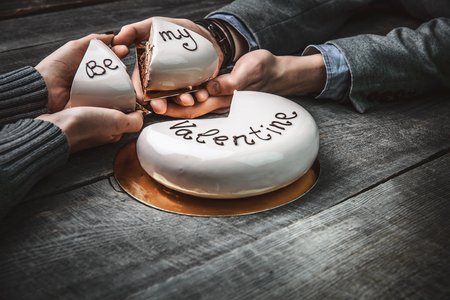 Beautiful cake with the words Be My Valentine for Valentine's day in the hands of a loving coupleの写真素材